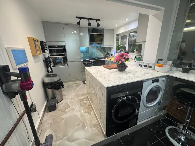 Modern grey gloss kitchen with marble waterfall island and integrated appliances, South London